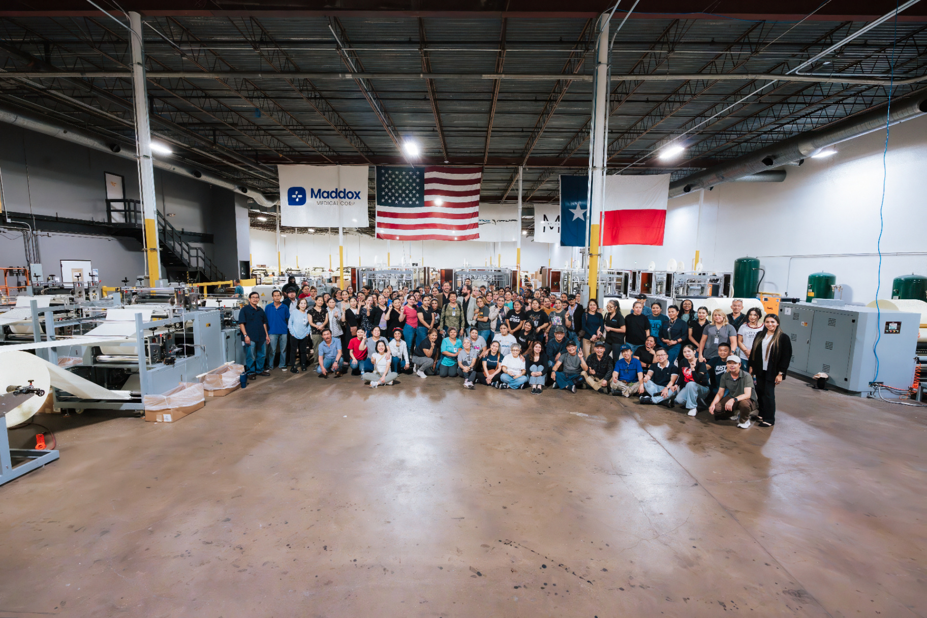 Wide Houston factory team photo showing the workforce gathered on the production floor beneath U.S. and Texas flags