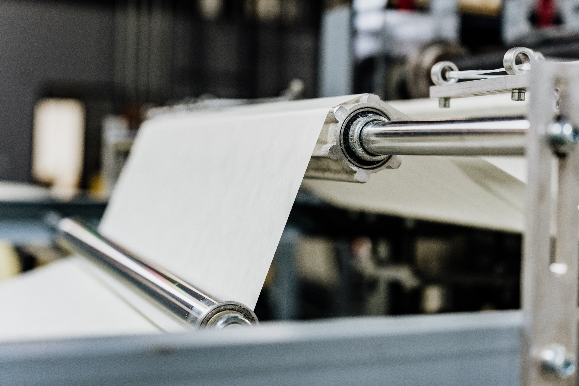 Close-up of nonwoven gown web running through stainless rollers